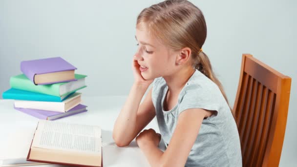 Portret profiel student meisje 7-8 jaar lezen boek en glimlachend in de camera. Bovenaanzicht. Geïsoleerd — Stockvideo