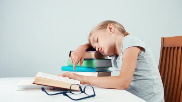 Chica de la escuela de retratos 7-8 años durmiendo en la pila de libros. Aislado sobre blanco — Vídeo de stock