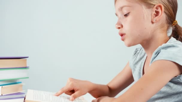 Extreme Nahaufnahme Porträt Mädchen Kind 7-8 Jahre alt Lehrbuch lesen und lächelnd mit Zähnen. Vereinzelt. Schwenken — Stockvideo