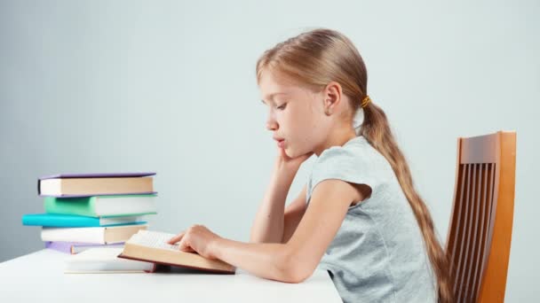 Portrait profile girl child 7-8 years old reading textbook and smiling at camera with teeth. Isolated — Stock video