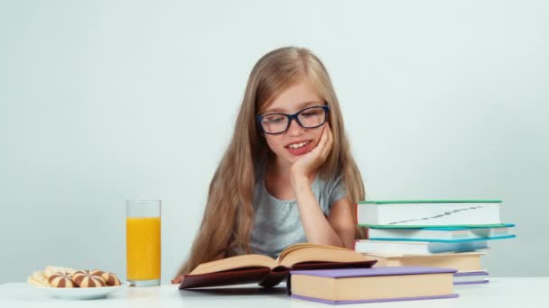 Portret schoolmeisje 7-8 jaar oud in glazen leerboek over de tabel lezen — Stockvideo