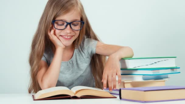 Портрет милая студентка с длинными светлыми волосами 7-8 лет в очках читает книгу и смотрит в сторону — стоковое видео