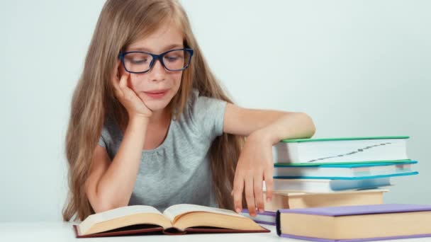 Close up portrait cute student girl with long blond hair 7-8 years in glasses reading book and smiling — Αρχείο Βίντεο