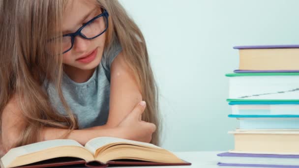 Extremo close up retrato bonito estudante menina com cabelo loiro longo 7-8 anos em óculos livro de leitura — Vídeo de Stock