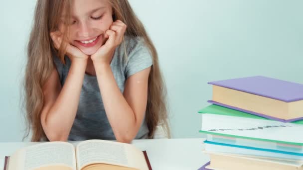 Портретная школьница 7-8 лет читает книжку крупным планом и улыбается зубами перед камерой. Паннинг — стоковое видео