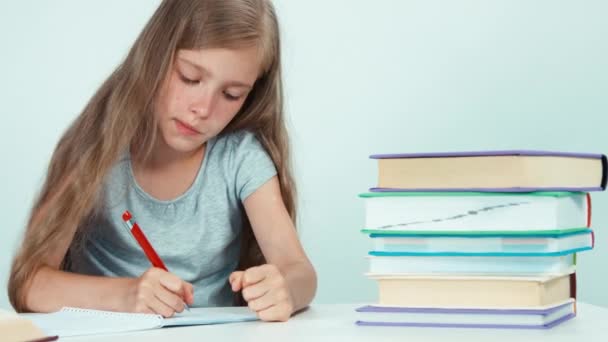 Menina algo escrevendo em seu caderno e olhando para a câmera. Isolado em branco. Panning — Vídeo de Stock