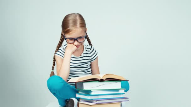 Ragazza della scuola che legge un libro e si estende guardando la fotocamera seduta sul pavimento — Video Stock