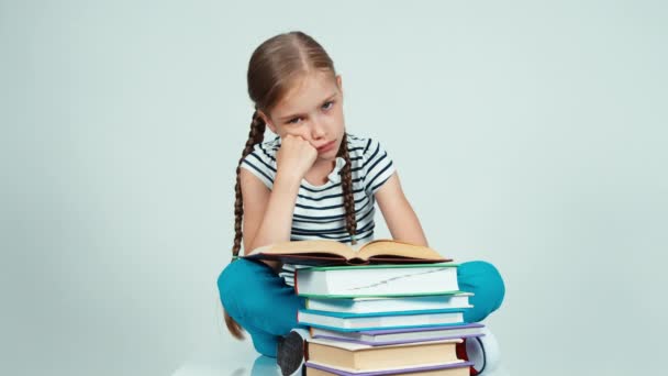 Portrait sad schoolgirl reading a book and stretching and sitting on the floor — Stock Video