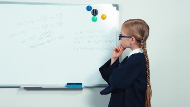 Nerd standing near whiteboard and thinking. Student girl smiling at camera — Stock video