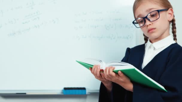 Close up hands little student girl holding book near whiteboard — Stock Video