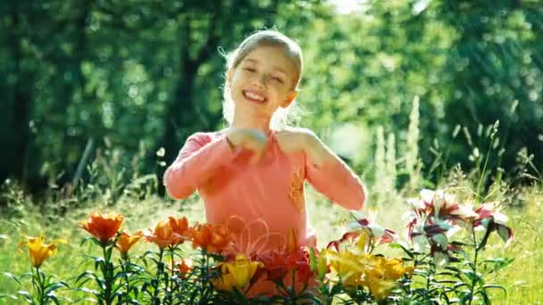 Close-up portret meisje 7-8 jaar oude staande spelen onder de sprinkler in de tuin in zonnige dag. Kind lachend op camera — Stockvideo