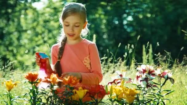 Portrait girl sprinkler her flowers in the garden and sniffing their — Stock video