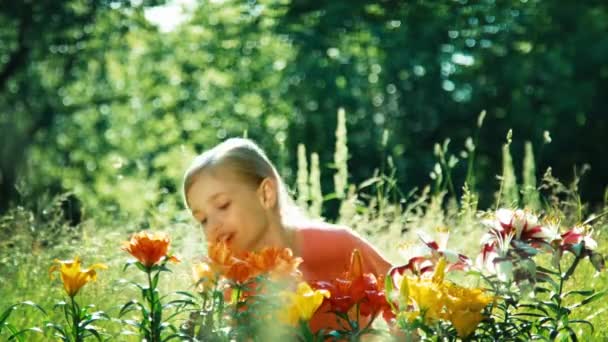 Nahaufnahme Porträt Mädchen singt ein Lied ihre Blumen und schnüffelt ihre im Garten — Stockvideo