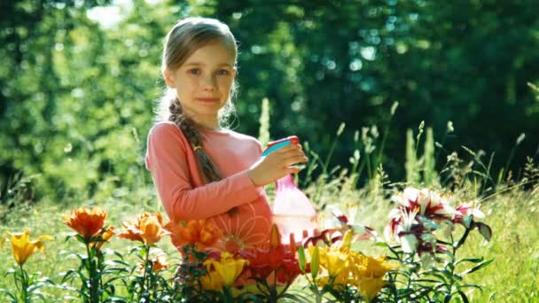 Menina retrato polvilhando na câmera perto de suas flores no jardim. Polegar para cima. Está bem. — Vídeo de Stock