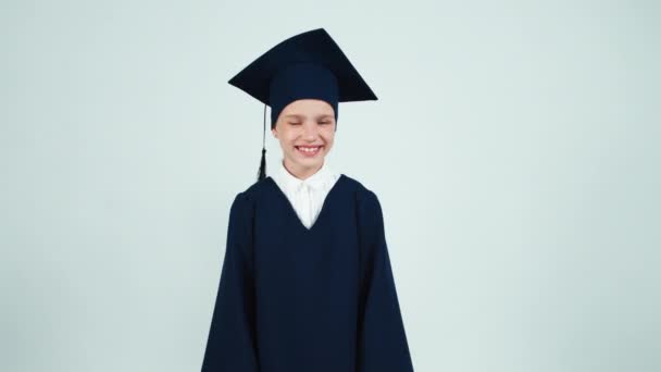 Портрет счастливая выпускница 7-8 лет в мантии улыбается зубами перед камерой — стоковое видео