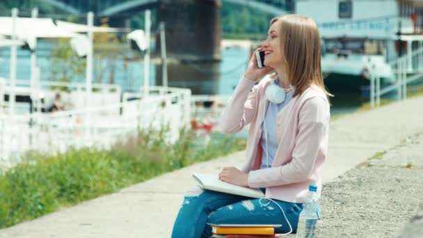 Mujer adulta joven hablando por teléfono móvil y utilizando la tableta PC al aire libre — Vídeos de Stock