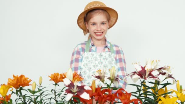 Cerrar retrato flor-chica en sombrero usando aspersor y rociando flores en la cámara y sonriendo con los dientes — Vídeos de Stock