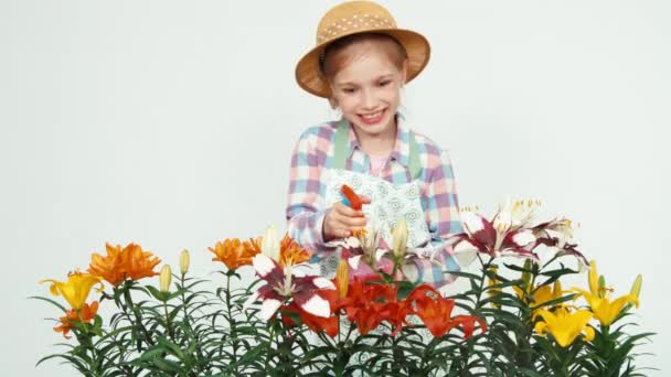 Blomma-flicka i hatt strö blommor på kameran och ler med tänder på vit — Stockvideo