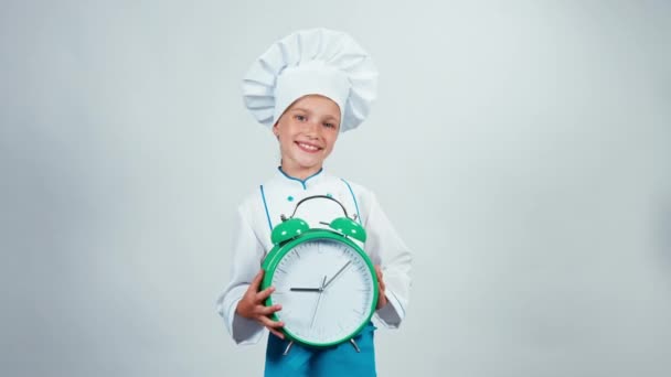 Alarm clock ringing. Little chef cook holds big alarm clock standing on white background looking at camera — Stock Video