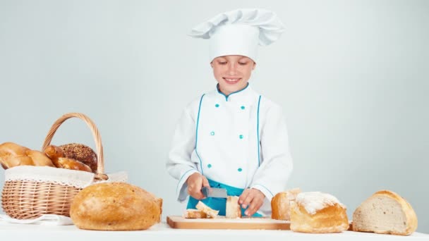 Baker, cięcia i jedzenie kromka chleba na białym tle — Wideo stockowe