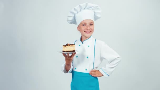 Baker entre dans le cadre avec un biscuit au chocolat et vous le donne. Chef 7-8 ans souriant à la caméra. Isolé sur fond blanc. Levez le pouce. D'accord. — Video