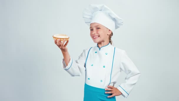 Baker segurando em suas mãos pequeno bolo com creme e dá-lhe. Chef 7-8 anos sorrindo para a câmera. Isolado sobre fundo branco — Vídeo de Stock