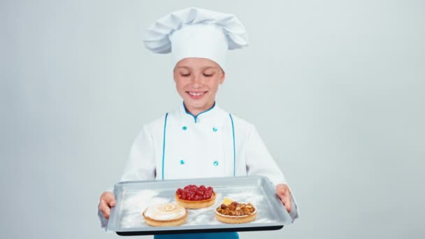 Baker tartja a sütő-tálcát három kis sütit és mosolyogva elszigetelt fehér kamera — Stock videók