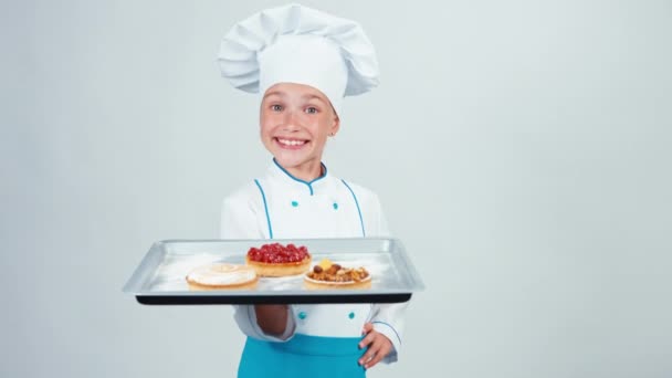 Bäcker hält Backblech mit drei kleinen Kuchen und lächelt in die Kamera isoliert auf weißem Hintergrund. Daumen hoch. ok — Stockvideo