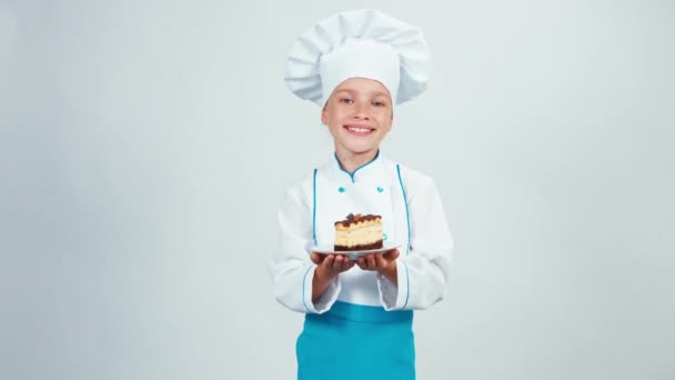Baker tiene piatto con biscotto al cioccolato e te lo dà. Chef 7-8 anni sorridente alla macchina fotografica. Isolato su sfondo bianco — Video Stock