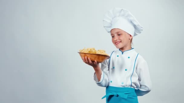 Kucharz kucharz dziecko 7-8 lat posiada płyta z makaronem, stojąc na białym tle na białym tle i w aparacie — Wideo stockowe