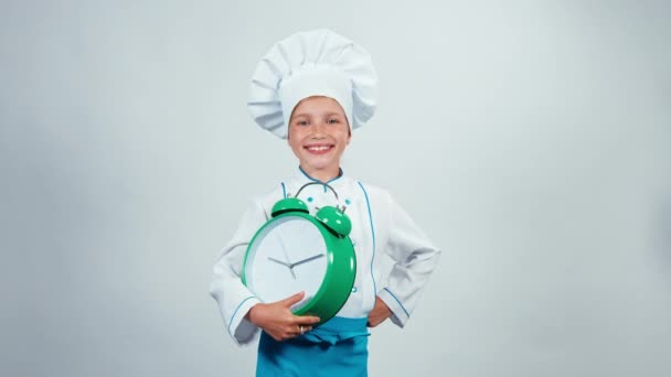 Kucharz kucharz dziecko 7-8 lat, wskazując budzik i stojąc na białym tle na białym tle — Wideo stockowe