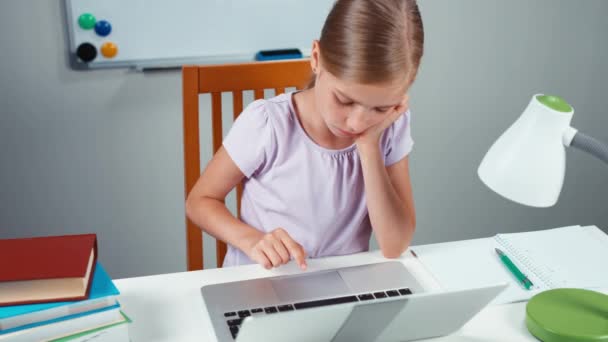 Gyermek lány 7-8 éve használ laptop az asztalára, és mosolyogva kamera. Szemközti nézet — Stock videók
