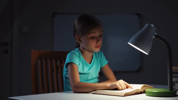Kind geeuwen en lezen van een boek in de nacht en glimlachend op camera — Stockvideo