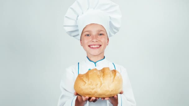 クローズ アップの肖像画のパン屋彼女の手で丸いパンを保持し、白で隔離のカメラに笑顔を与える — ストック動画