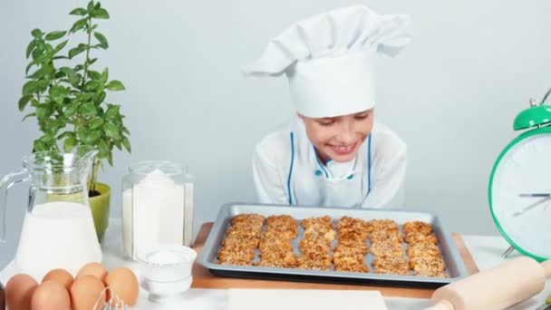 Close-up portret chef kok meisje kind 7-8 jaar oud heeft bakken dienblad met koekjes en lachend op camera — Stockvideo