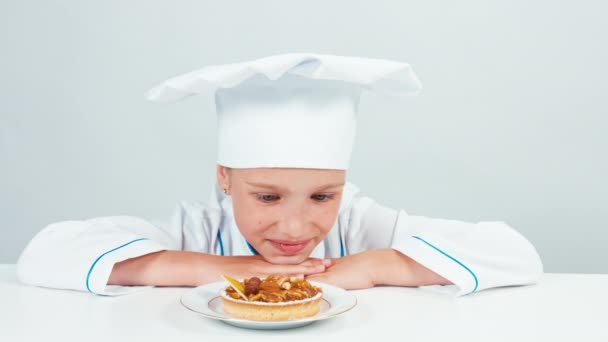 Gros plan portrait visage de boulanger examinant petit gâteau à la crème et souriant à la caméra isolé sur fond blanc — Video