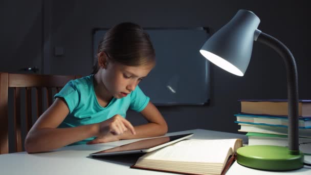 Close up retrato menina criança 7-8 anos de idade usando tablet pc na noite em sua mesa e sorrindo para a câmera — Vídeo de Stock