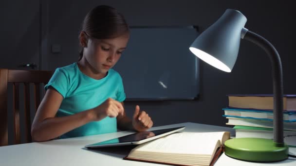 Portre kız çocuk 7-8 yaşında masasına gecede tablet kullanarak kapatın. Yukarı başparmak. Tamam — Stok video