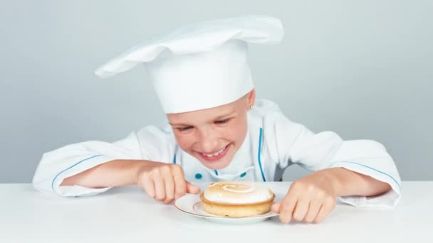 Close up retrato cozinheiro chef pequeno feliz olhando para o bolo pequeno com e sorrindo para a câmera — Vídeo de Stock