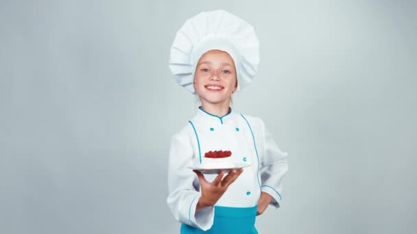 Крупним планом портрет маленького кухаря, який тримає торт з печивом, дає вам і посміхається на камеру. Палець вгору. гаразд — стокове відео