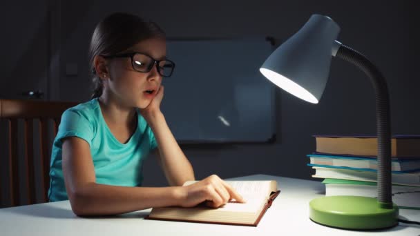 Närbild porträtt Skolflicka 7-8 år läser en bok och titta på fönstret — Stockvideo