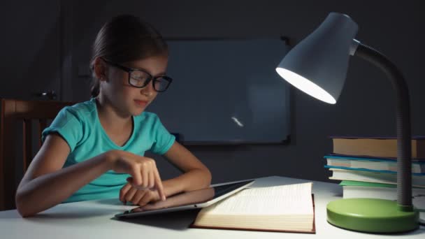 Крупним планом портрет школярки 7-8 років використовуючи планшетний ПК вночі і посміхаючись на камеру — стокове відео