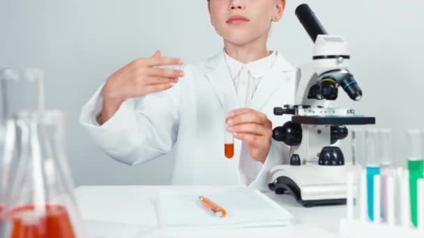 Close up retrato jovem estudante de química 7-8 anos segurando tubo de ensaio e cheirando produtos químicos. Isolado em branco — Vídeo de Stock