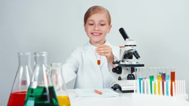 Acercamiento retrato joven farmacia escuela chica sosteniendo tubo de ensayo y oler productos químicos. Aislado sobre blanco — Vídeos de Stock