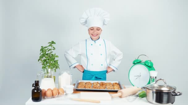 glückliche Köchin Kochmädchen 7-8 Jahre alt hat Backblech mit Keksen und lächelt in die Kamera. isoliert auf weiß