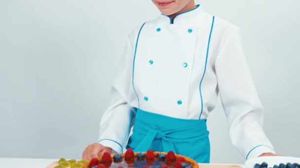 Pequeno cozinheiro chef decorar o bolo usando doces — Vídeo de Stock