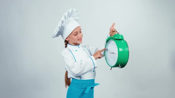 Little chef cook holds big alarm clock standing on white background looking at camera. Thumb up. Ok — Stock Video