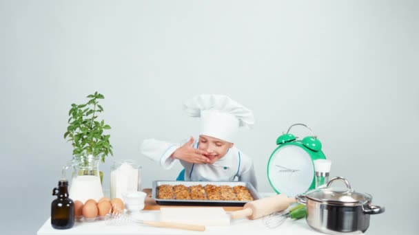 Retrato chef cocinera niña de 7-8 años olfateando galletas y sonriendo a la cámara. Aislado sobre blanco. Pulgares arriba. Ok. — Vídeo de stock