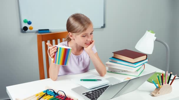 Portrait child 7-8 years looking at laptop and holding cup of tea and looking at camera with smile — Stock Video