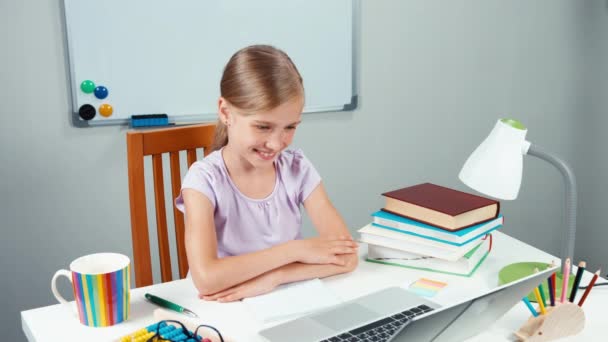 Portraitkind 7-8 Jahre hebt die Hand. Studentin sitzt auf ihrem Schreibtisch — Stockvideo